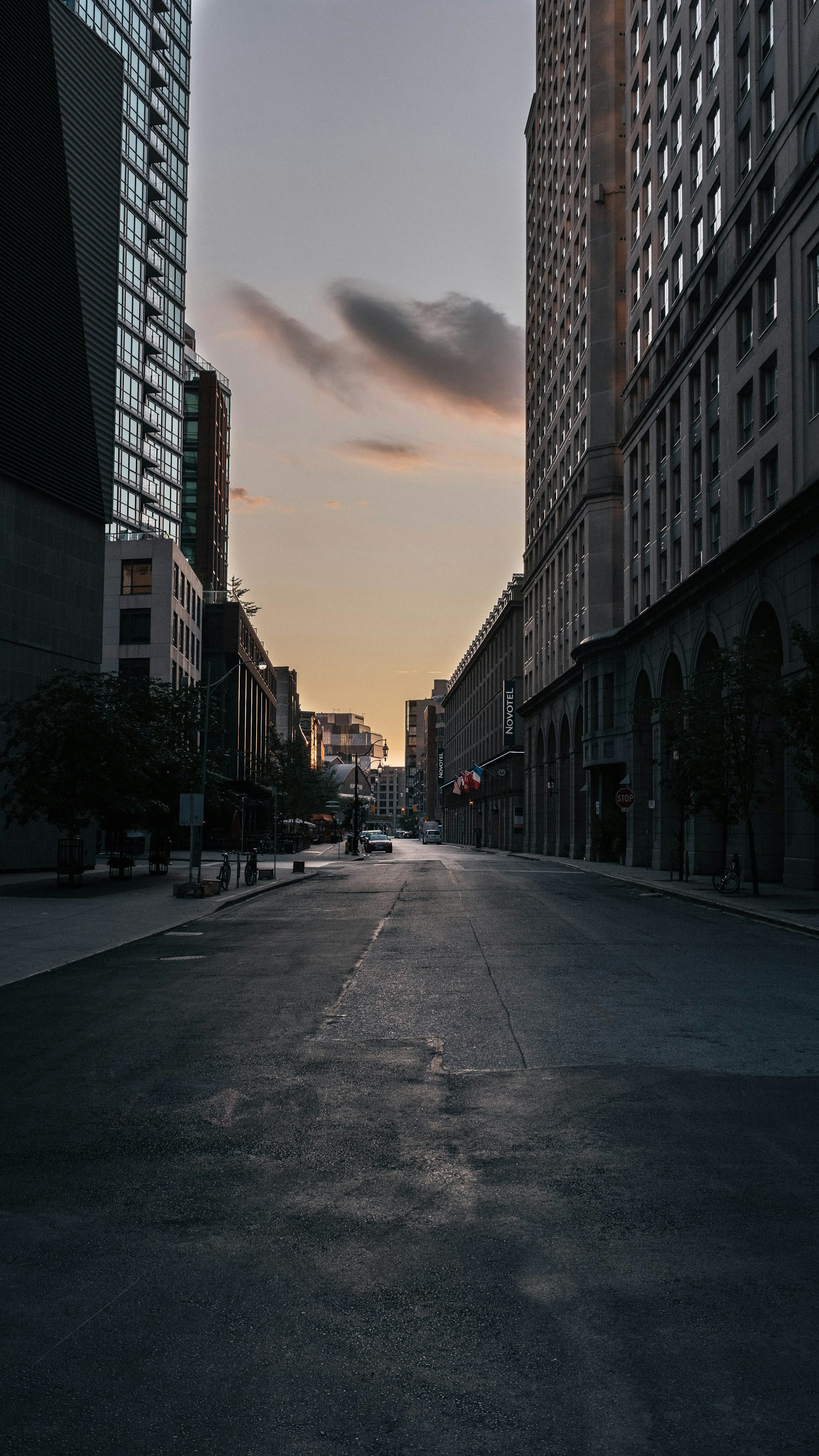 Tall buildings enclosing a quiet street under a low evening cloud