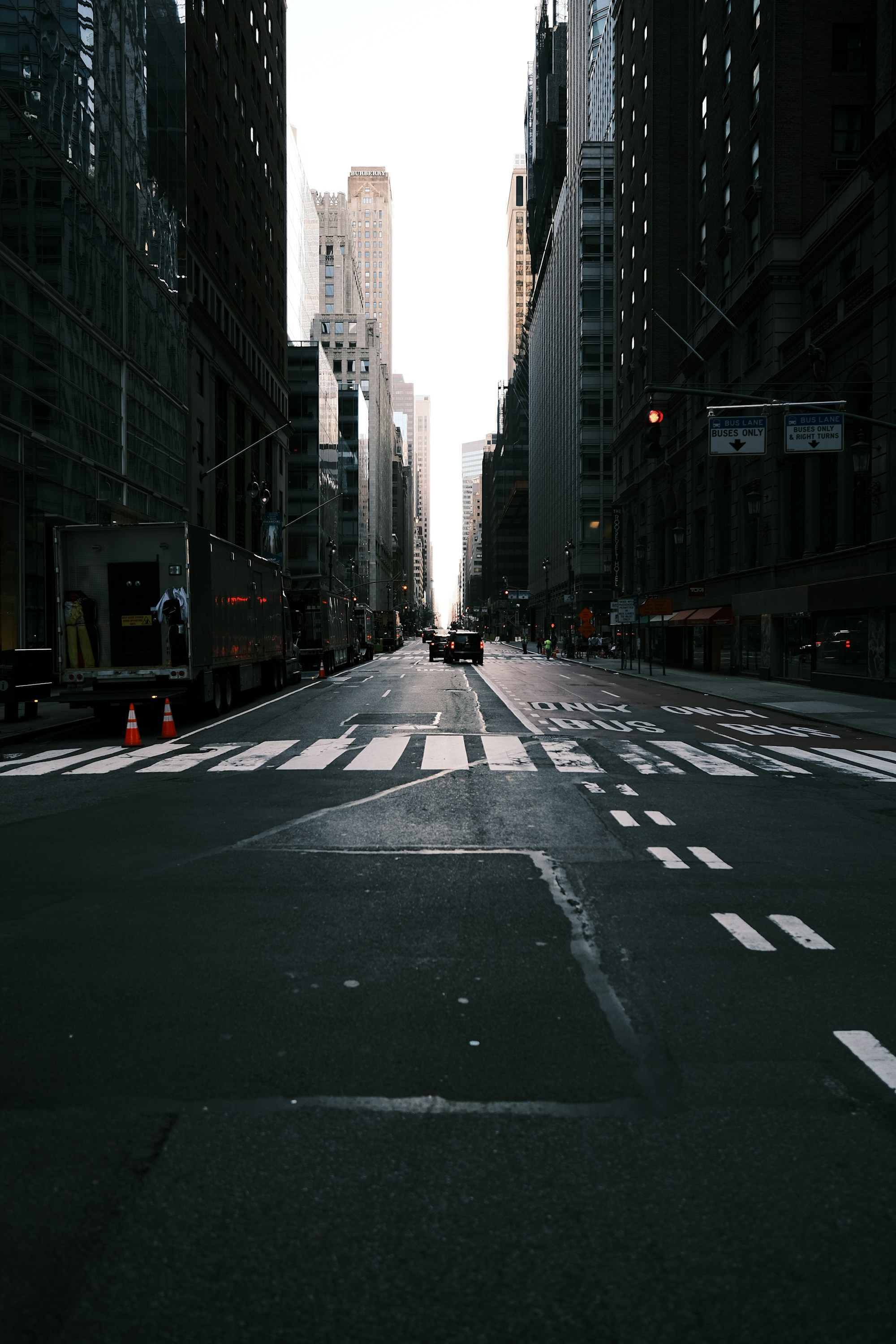 A dark New York avenue opening toward a bright strip of sky